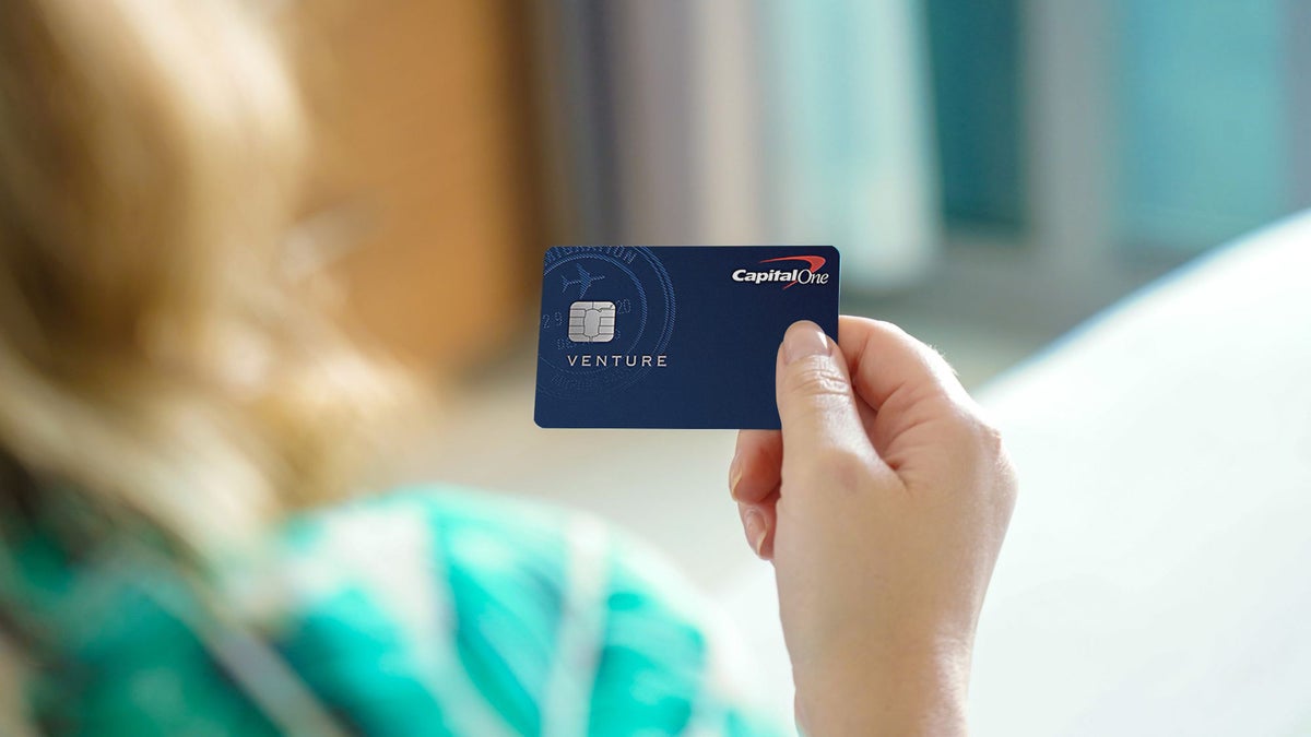 Female hand holding Capital One Venture Card Upgraded Points LLC