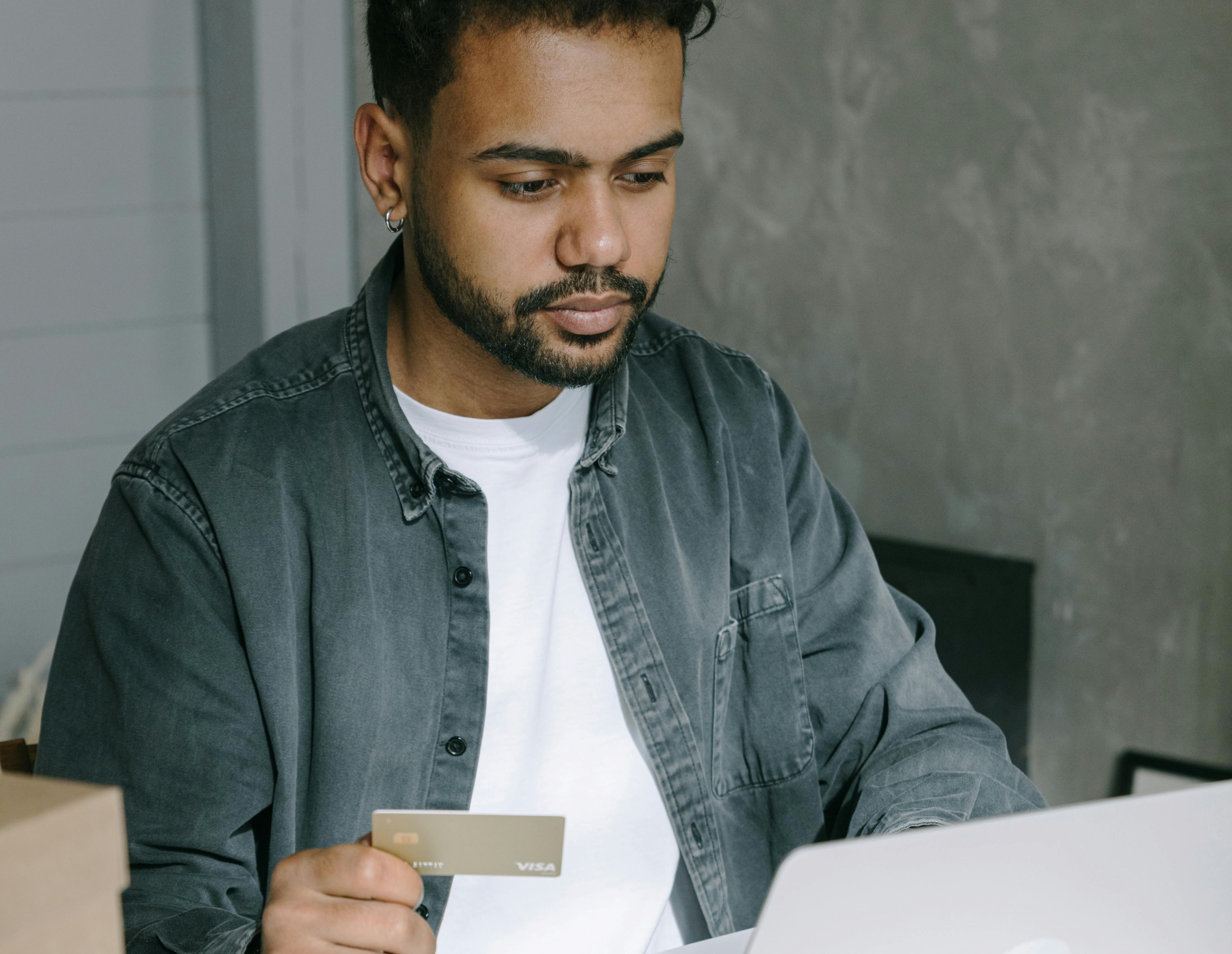 Man holding credit card using computer Man holding credit card using computer